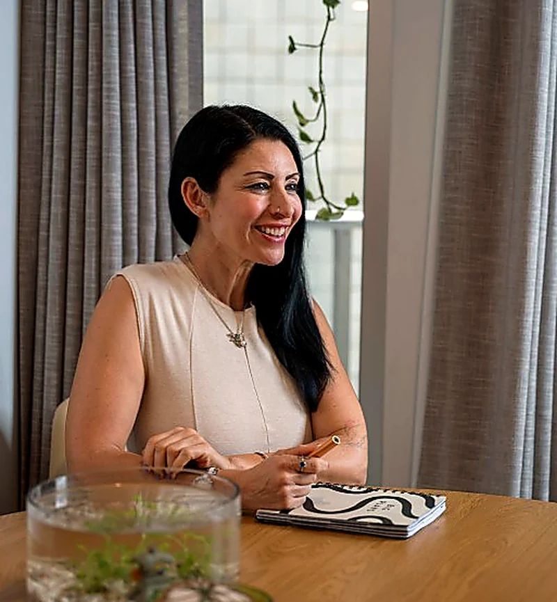 Janina smiling warmly at a table with a notebook and pen